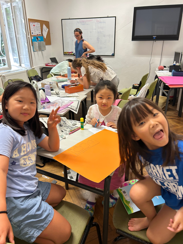 Young learners work on colourful craft projects during an English summer classroom activity.